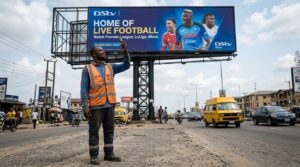 billboard installation worker standing on the ground directly below a freshly mounted billboard